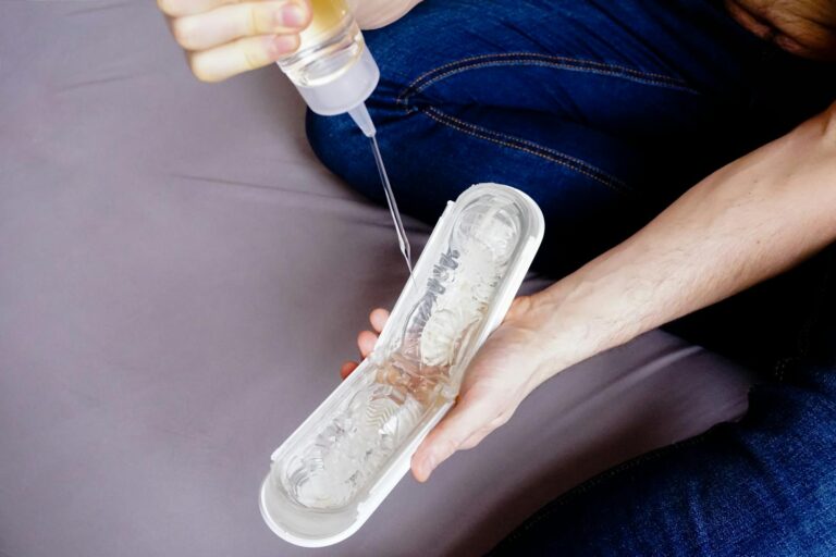 Hands holding an adult toy while applying lubricant, showcasing intimacy and sensuality.