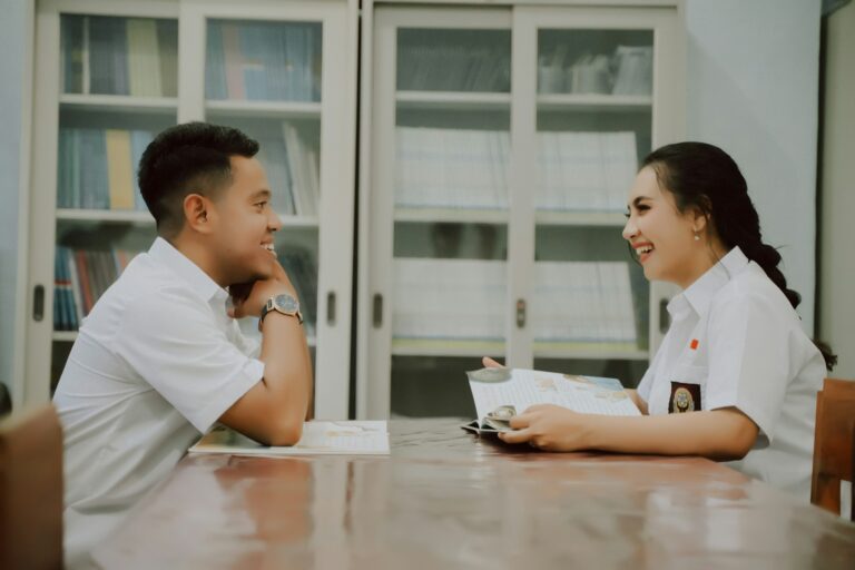 a man and a woman sitting at a table looking at a computer