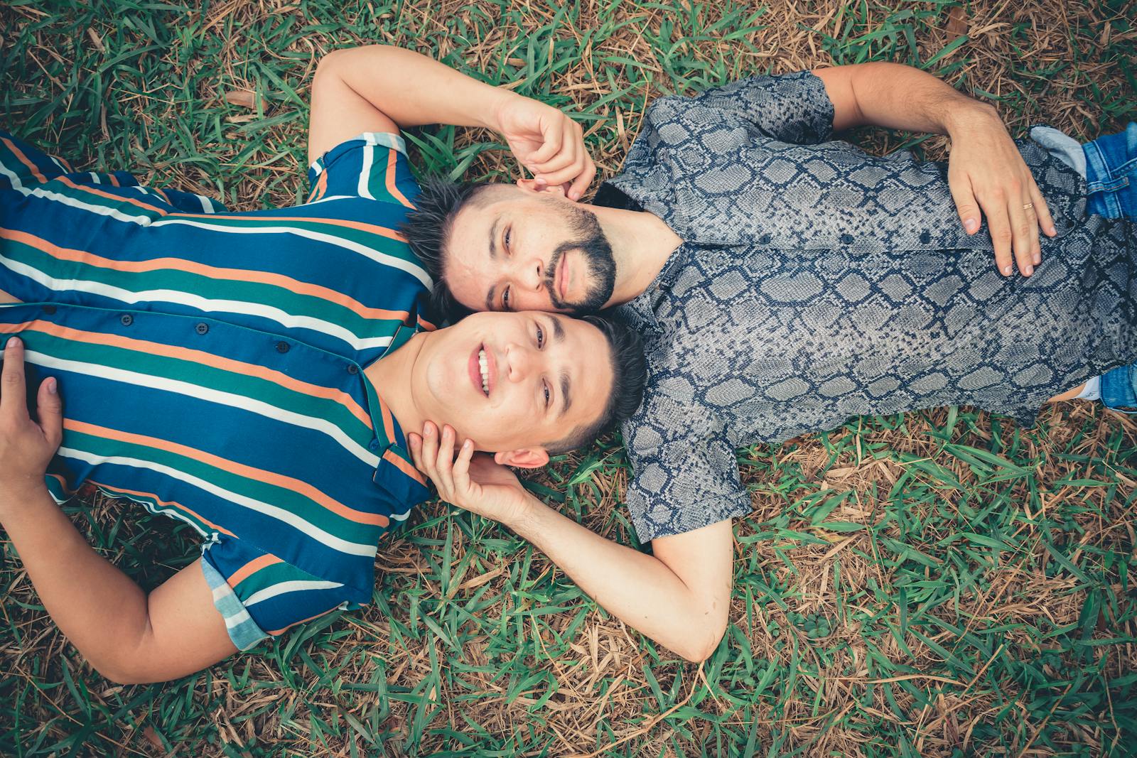 A happy couple enjoys a relaxing moment lying on grass outdoors in summer.