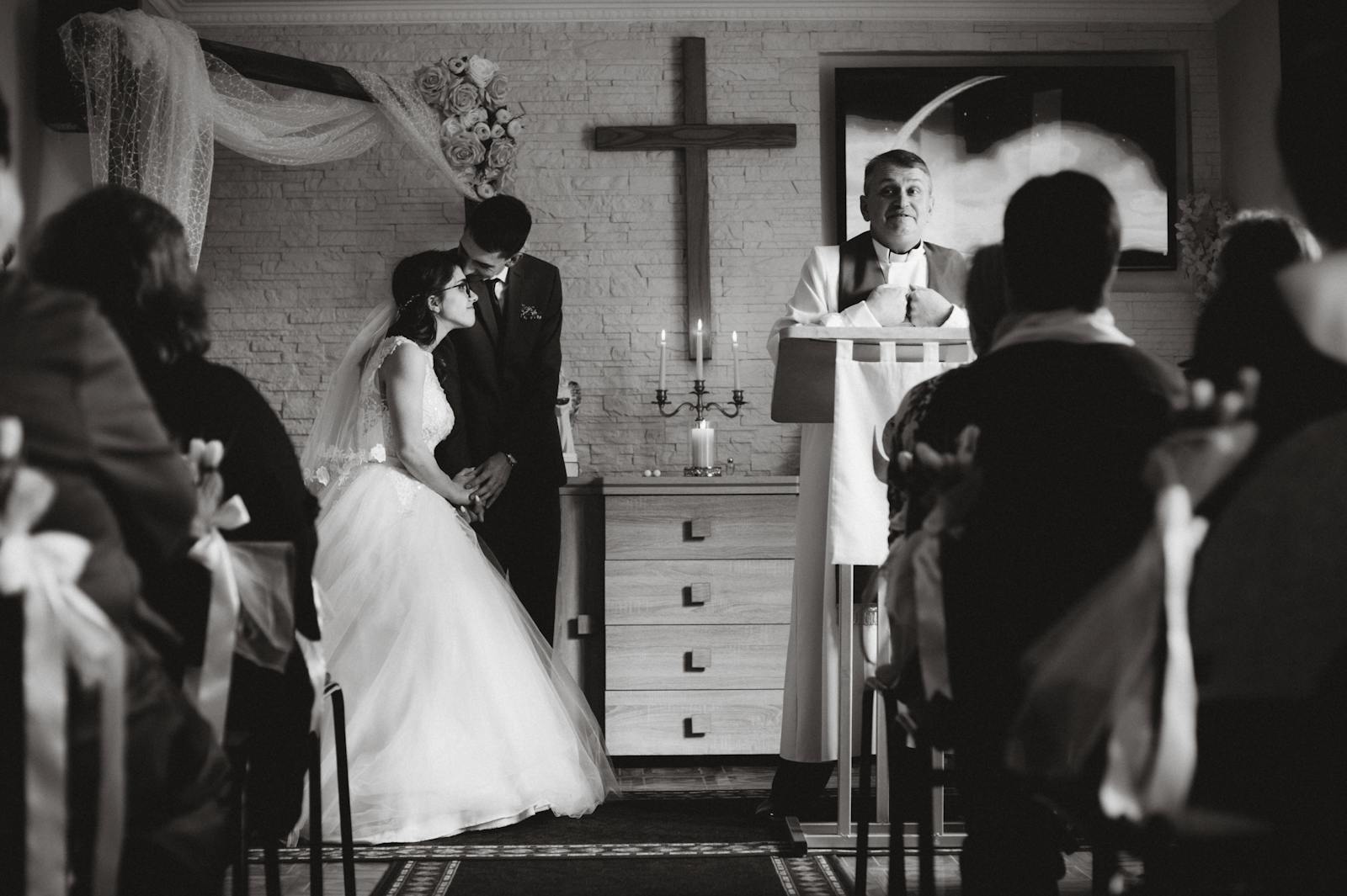 A romantic black and white photo of a wedding ceremony in a church setting.