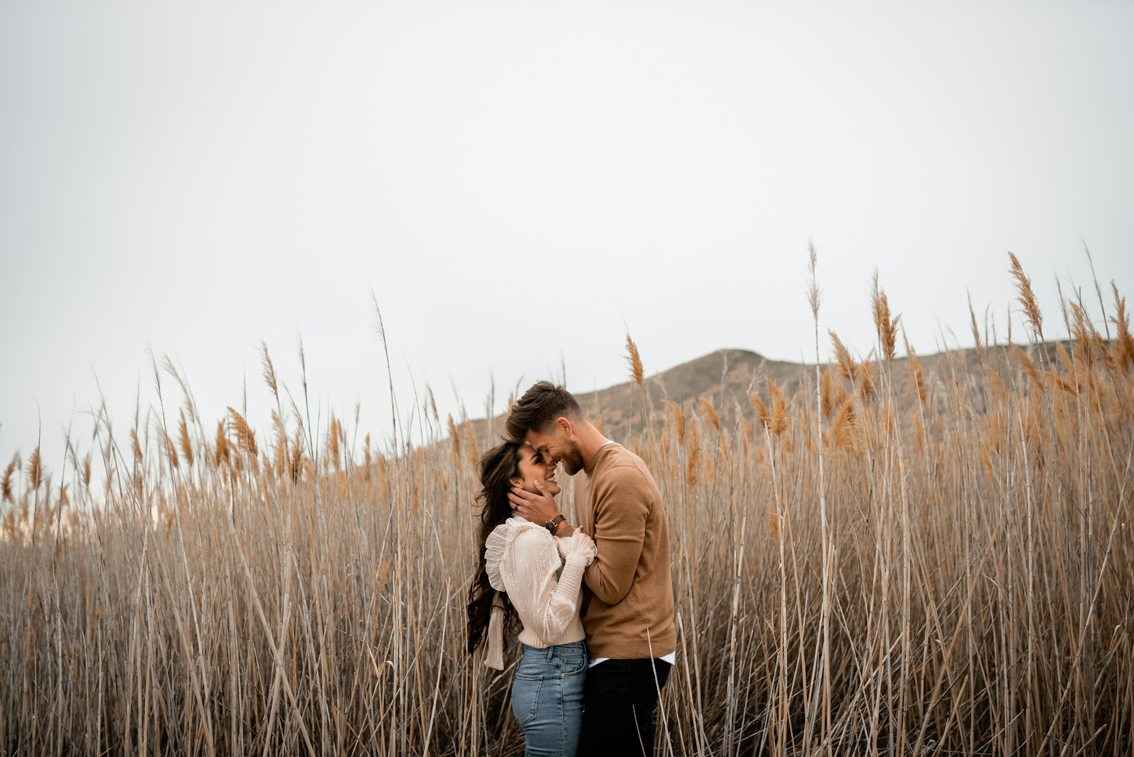 A man and a woman standing in a field of tall grass