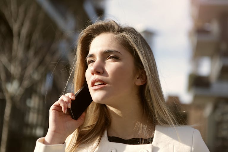 Young woman engaging in a phone call outdoors, capturing a moment of modern communication.