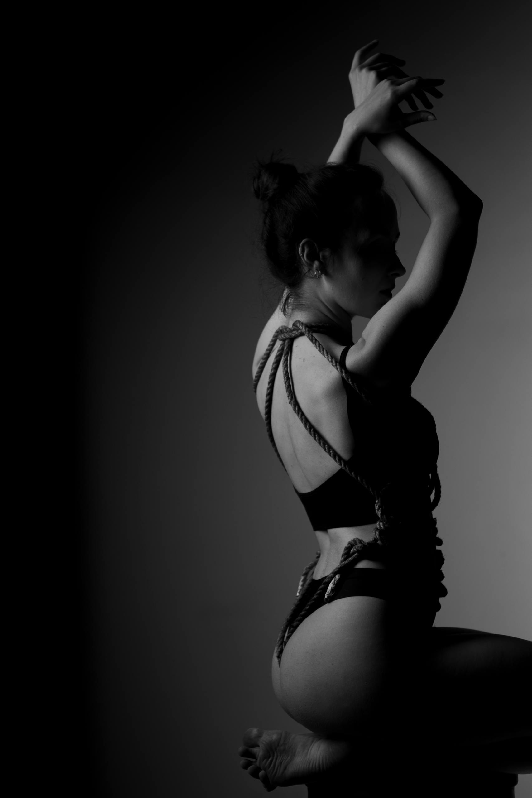 Dramatic black and white portrait of a woman in rope bondage, conveying sensuality and art.