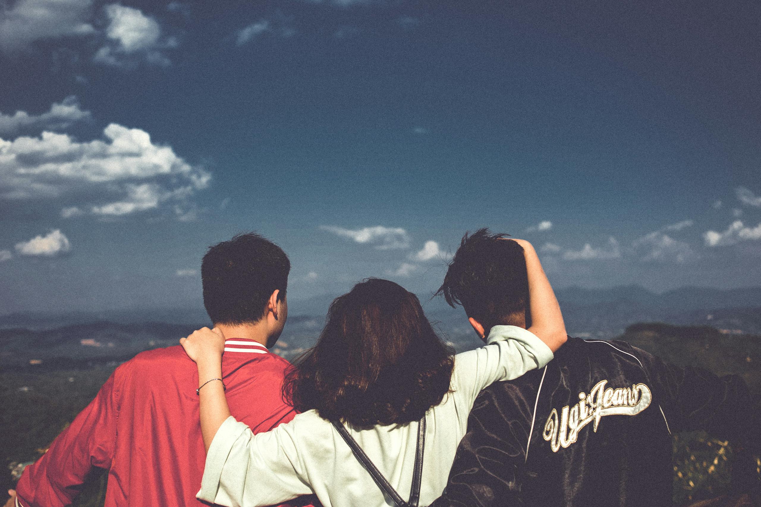 A group of three friends embracing and enjoying the scenic mountain view in Đắk Ya, Vietnam.