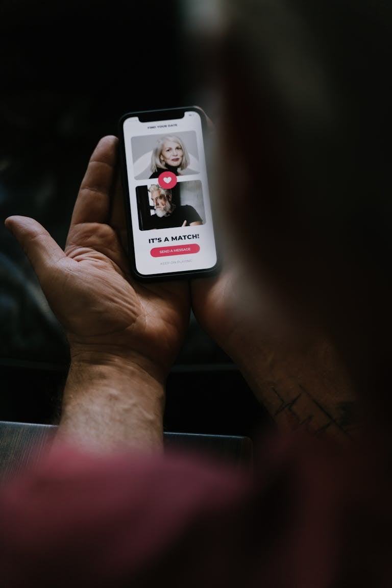 Close-up of hands holding a smartphone showing an online dating match.